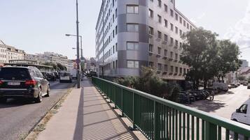 Um edifício de vários andares com design moderno, destacando-se pela fachada curva e numerosas janelas.