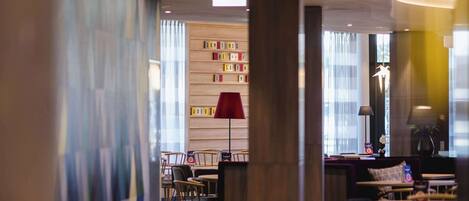 A modern hotel lobby with a curved ceiling, a reception desk, and seating areas.