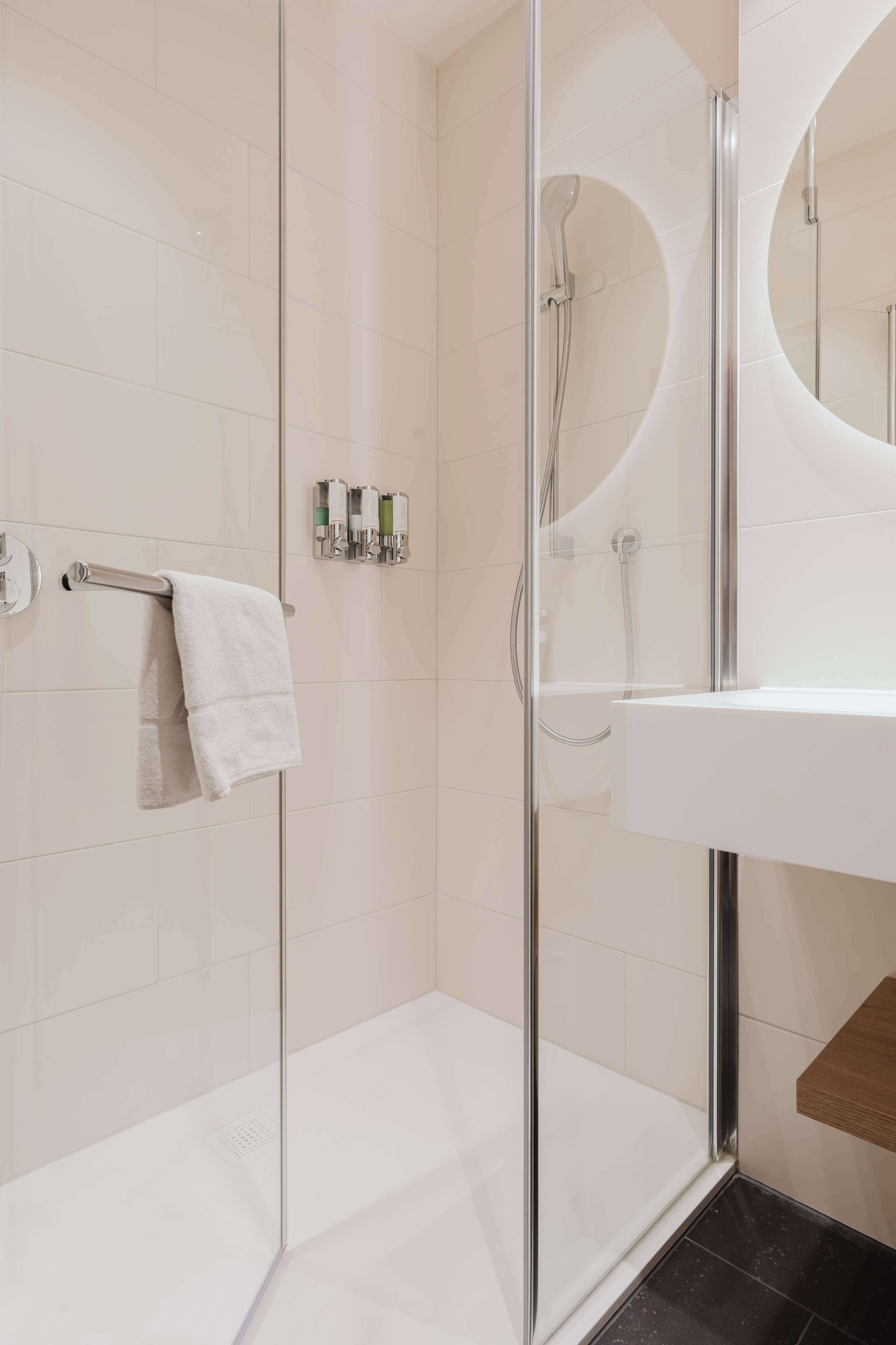 Une salle de bain moderne avec une douche à parois de verre, un lavabo blanc et un porte-serviettes.