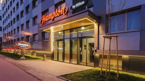 En moderne hotelindgang med et tydeligt skilt, glasdøre og en godt oplyst sti.