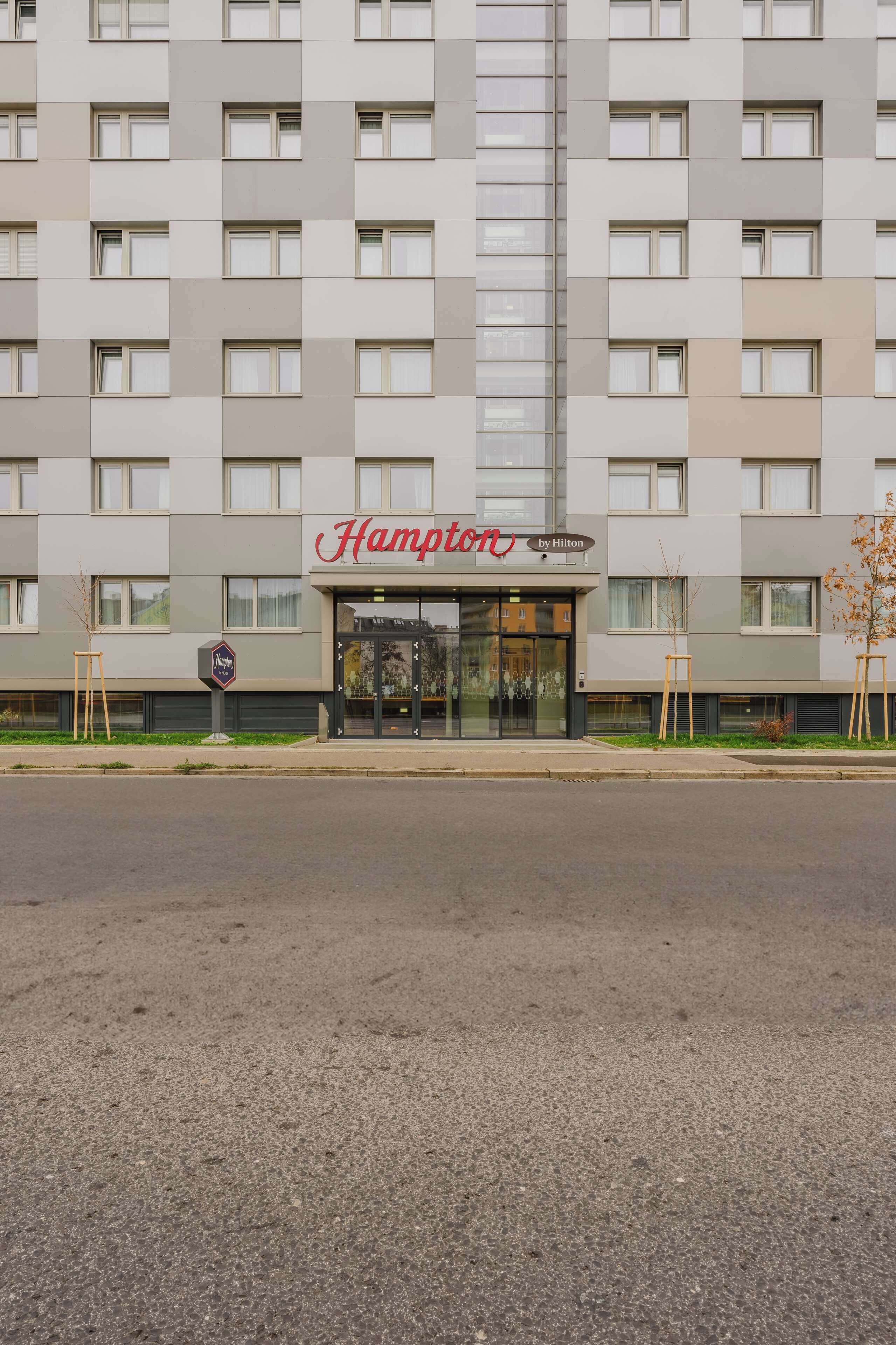 Fachada de un hotel Hampton by Hilton con diseño moderno, que presenta una entrada amplia y múltiples ventanas.