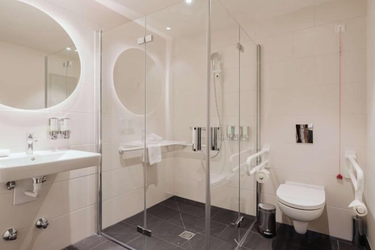 Un baño moderno con ducha envuelta en cristal, un lavabo blanco y un inodoro.