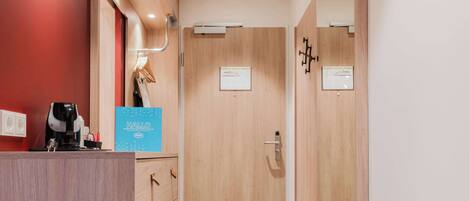 A hotel room with a wooden desk, a bed, a mirror, and a door leading to another room.