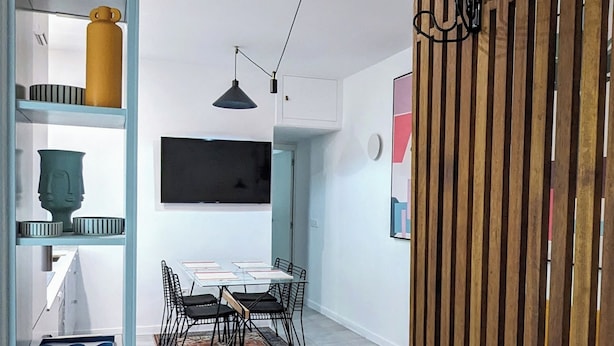 A modern interior with a dining area, a TV mounted on the wall, and a wooden partition. - Madrid Mola ! (Madrid)