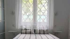 A bedroom with a bed, two bedside tables, a window with curtains, and a ceiling light fixture. - Madrid Mola ! (Madrid)