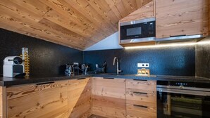 A modern kitchen with wooden cabinetry, a built-in microwave, and a stainless steel oven. - 2nd floor, view mountain, balcony, fireplace or stove, parking, tv, ski locker, 69m² (Méribel - Les Allues)