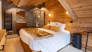 A bedroom with a wooden ceiling, a large bed with white bedding, a wooden dresser, a mirror, and a small bedside table. - 2nd floor, view mountain, balcony, fireplace or stove, parking, tv, ski locker, 69m² (Méribel - Les Allues)