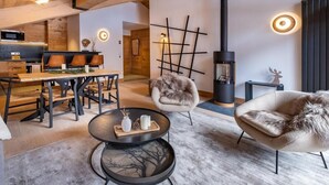 A modern living room with a wooden ceiling, a fireplace, a dining area with a wooden table and chairs, and a cozy seating area with a fur-covered armchair. - 2nd floor, view mountain, balcony, fireplace or stove, parking, tv, ski locker, 69m² (Méribel - Les Allues)