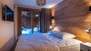 A bedroom with a large bed, wooden panel walls, a ceiling light, and a view of a snowy outdoor area. - 2nd floor, terrace, fireplace or stove, parking, tv, ski locker, 95m², Méribel-Mottaret (Méribel - Les Allues)