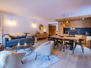A modern living room with a sofa, coffee table, and dining area.