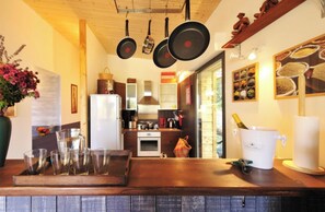 A kitchen with hanging pots, a refrigerator, a stove, and a coffee machine.