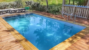 A rectangular swimming pool with a wooden deck surrounding it. - Ecolodge calme & piscine privée (Roquetaillade-et-Conilhac)