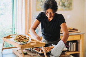 A person preparing food on a wooden table with a tray and a baking sheet.