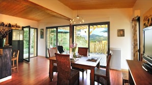 A dining area with a wooden table and chairs, a television, and a view of the outdoors. - Ecolodge calme & piscine privée (Roquetaillade-et-Conilhac)