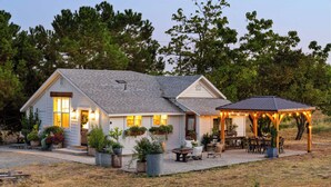 A house with a covered patio, outdoor seating, and potted plants.