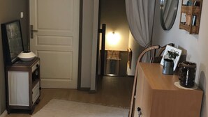 Ein Flur mit einer weißen Tür, auf der “PRIVE” steht, einer Holzkommode mit Spiegel und Ablagefläche sowie einem weißen Teppich.