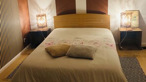 Ein ordentlich bezogenes Bett mit zwei Kissen, einem Holz-Kopfteil und zwei Nachttischlampen mit dekorativen Lampenschirmen.