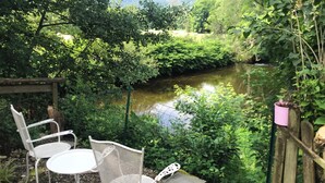 Ein Garten mit Teich, zwei weißen Metallstühlen und einem Holzzaun.