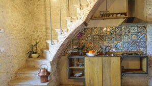 A rustic kitchen with a stone wall, a wooden staircase, and a tiled backsplash. - Borgo San Valentino  (Arrone)