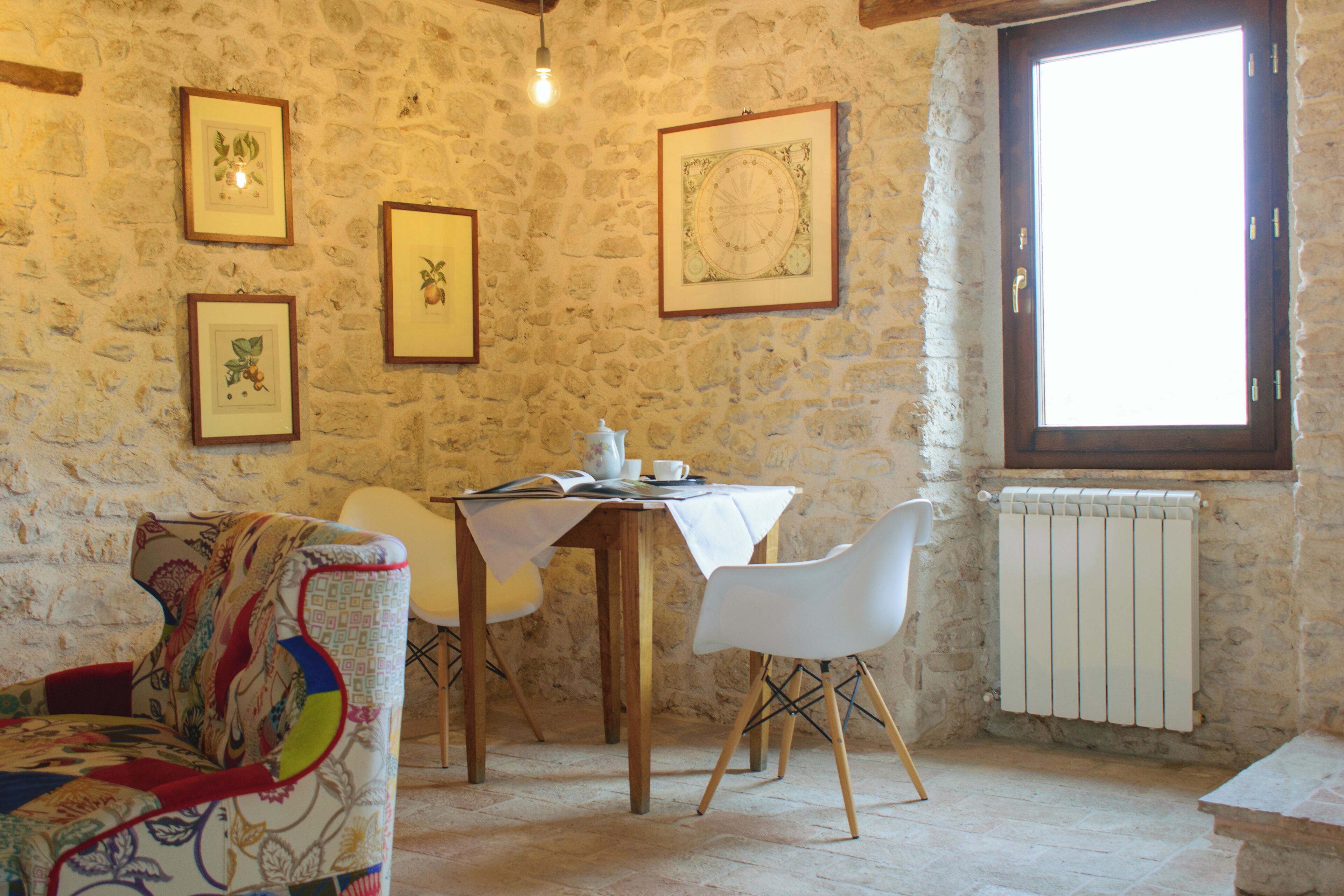Una stanza con pareti in pietra, un tavolo da pranzo, sedie e quadri appesi alle pareti.