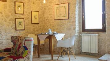 Una stanza con pareti in pietra, un tavolo da pranzo, sedie e quadri appesi alle pareti.