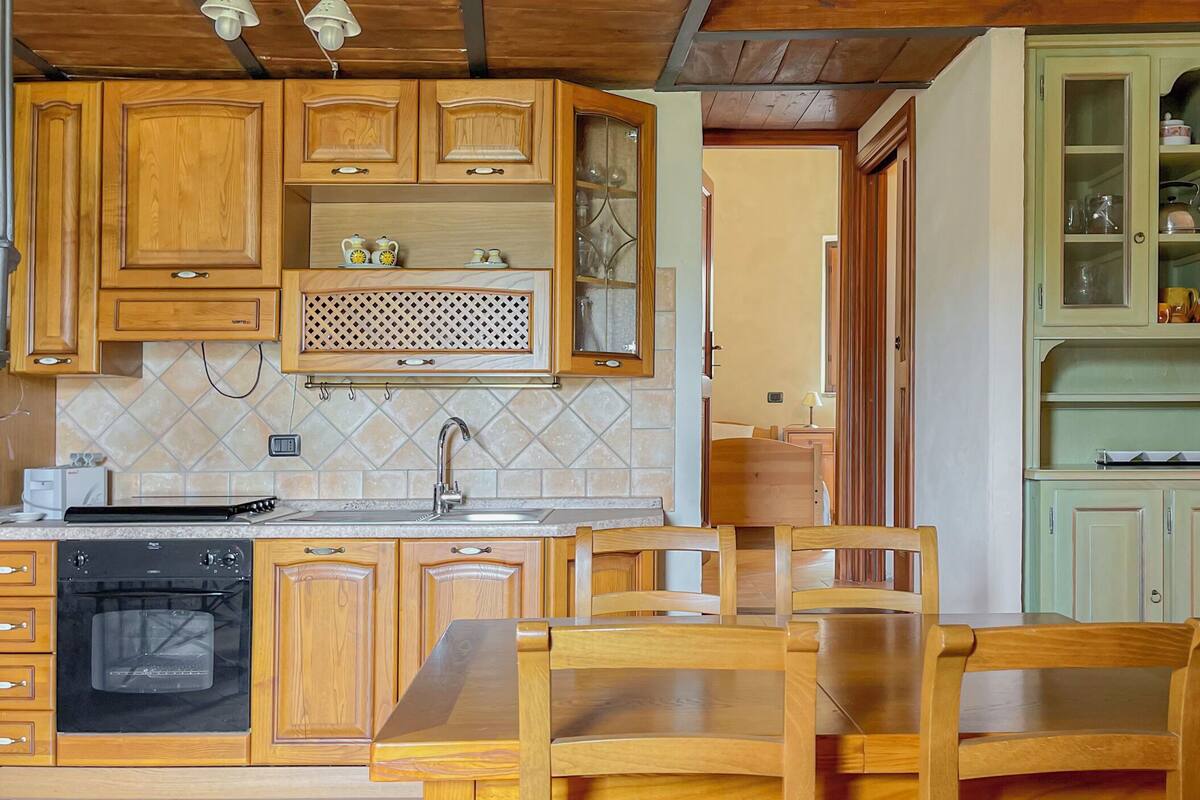 A kitchen with wooden cabinets, a sink, a stove, and a dining table with chairs.