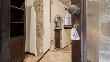 A stone archway leading to a staircase, a wooden door with a keychain, and a tiled floor.