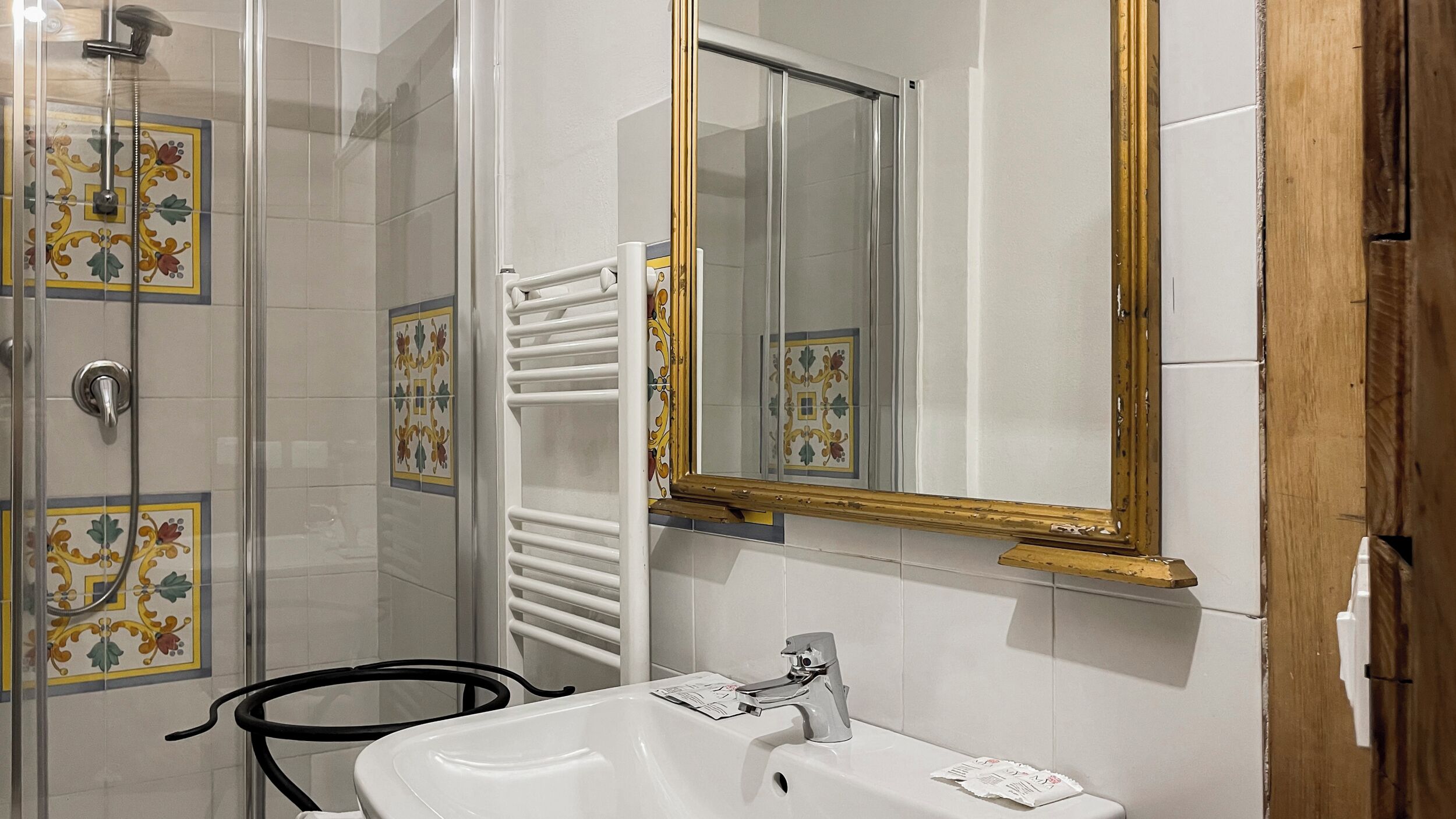 Une salle de bain équipée d’une douche, d’un lavabo, d’un miroir et d’un porte-serviettes.