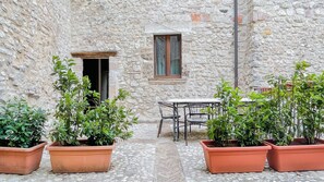 A stone building with a small table and chairs, surrounded by potted plants. - Borgo San Valentino (Arrone)