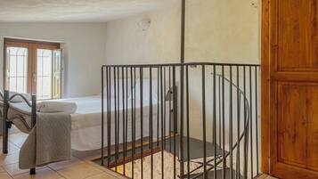 A room with a bed, a chair, a wooden door, and a metal gate.