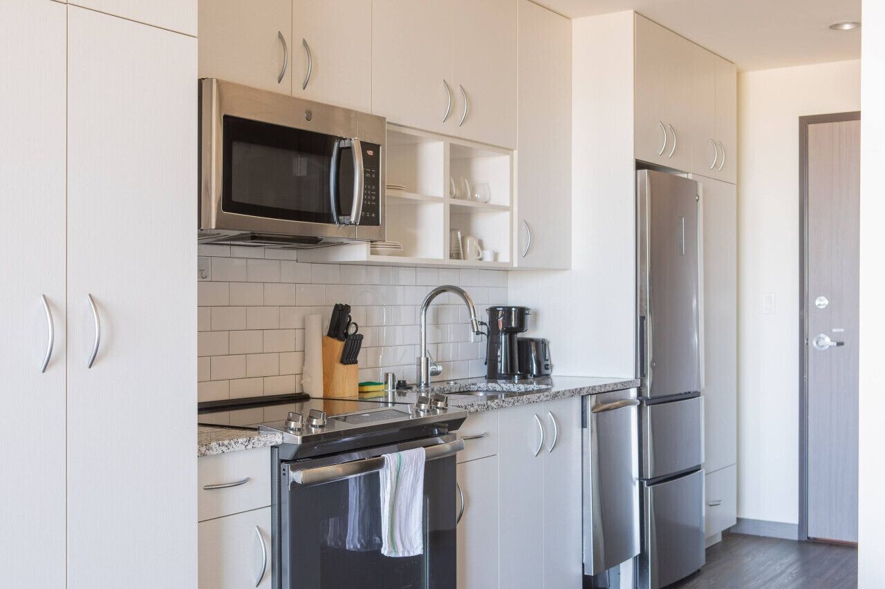 A modern kitchen with white cabinetry, stainless steel appliances, and a granite countertop.