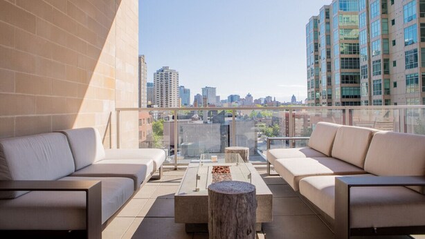 A balcony with a city view, furnished with sofas and a coffee table.