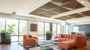 A modern living room with a sectional sofa, large windows, and a geometric ceiling design.