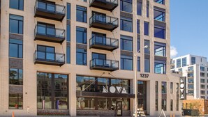 A multi-story building with balconies, large windows, and the name "NOVA" on the facade.