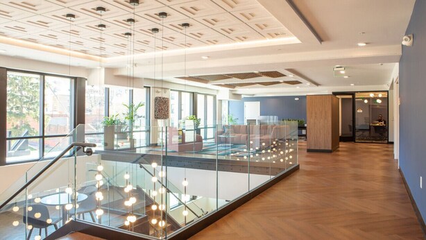 A modern interior with a glass staircase, wooden flooring, and a seating area with sofas and a coffee table.
