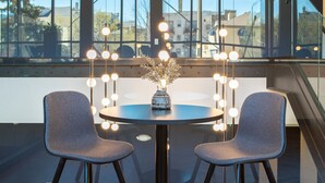 A modern dining area with a round table, two chairs, and a vase with flowers.
