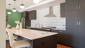 A modern kitchen with dark cabinets, a white countertop, and pendant lighting.