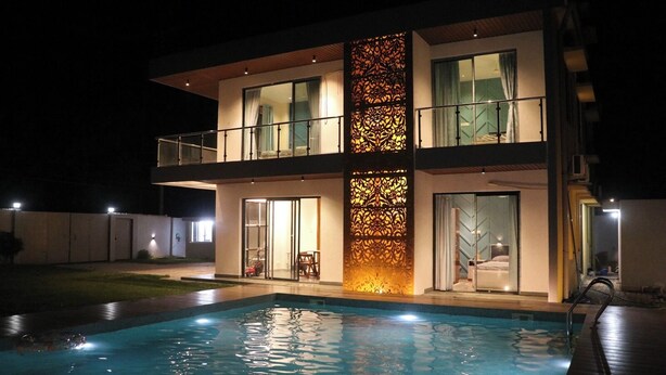 A modern two-story house with a swimming pool in the foreground.