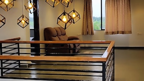 A spacious room with a high ceiling, a wooden ceiling design, and hanging geometric light fixtures.
