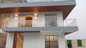 A modern two-story building with a balcony, large windows, and a staircase leading to the upper floor.