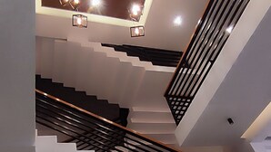 A modern staircase with geometric patterns, recessed lighting, and a plant arrangement at the bottom.