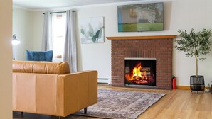 A living room with a brick fireplace, a sofa, a rug, and a plant. - Charming Catskill getaway walking distance to Main St. Pet-friendly! (Catskill)