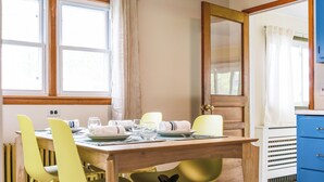 A dining area with a wooden table set for four, yellow chairs, and a blue cabinet. - Charming Catskill getaway walking distance to Main St. Pet-friendly! (Catskill)