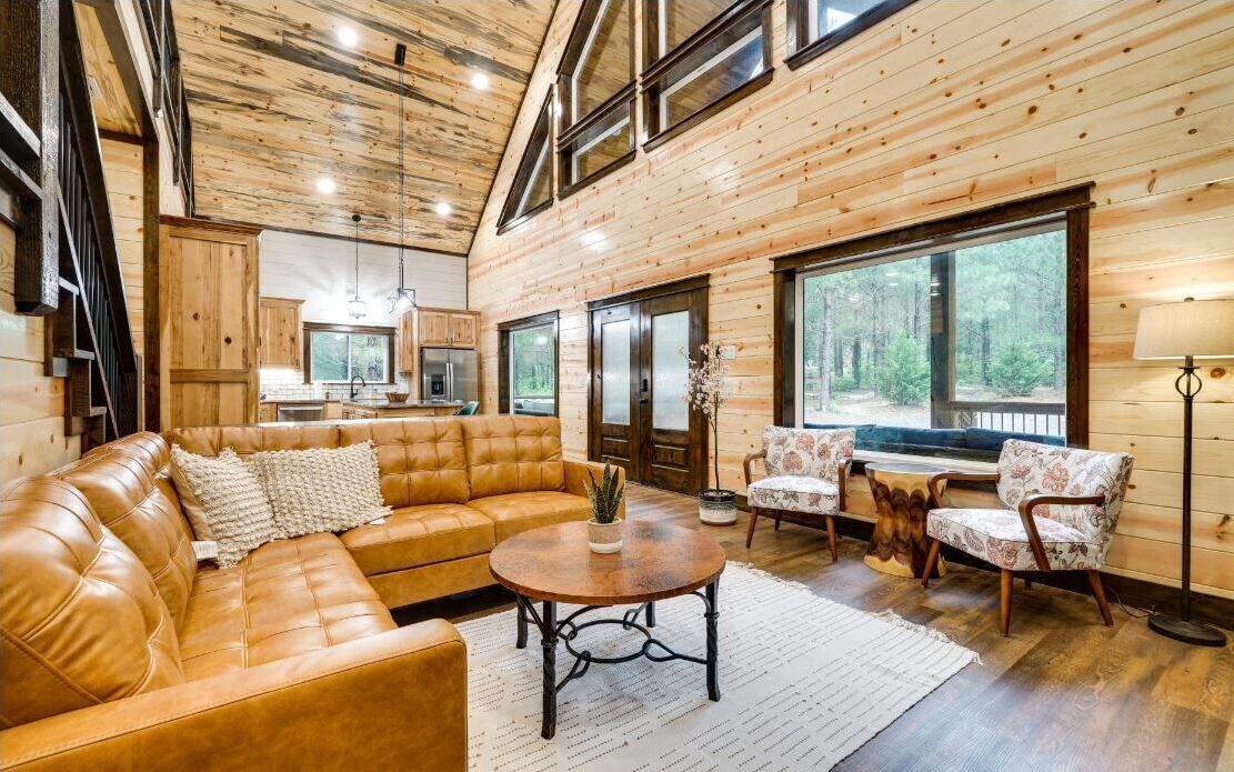 A cozy living room with a leather sofa, a round coffee table, and floral-patterned chairs.