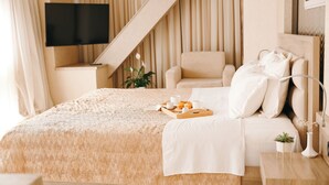 A neatly arranged bedroom with a bed, a bedside table, a chair, a TV mounted on the wall, and a staircase. - Hotel Partner & Spa (Vlorë)