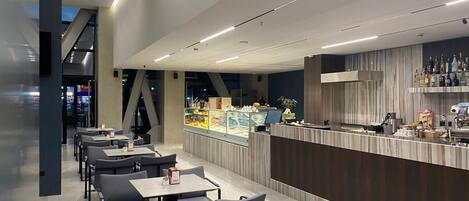 A modern restaurant with a long counter, seating area, and a display case with food items.