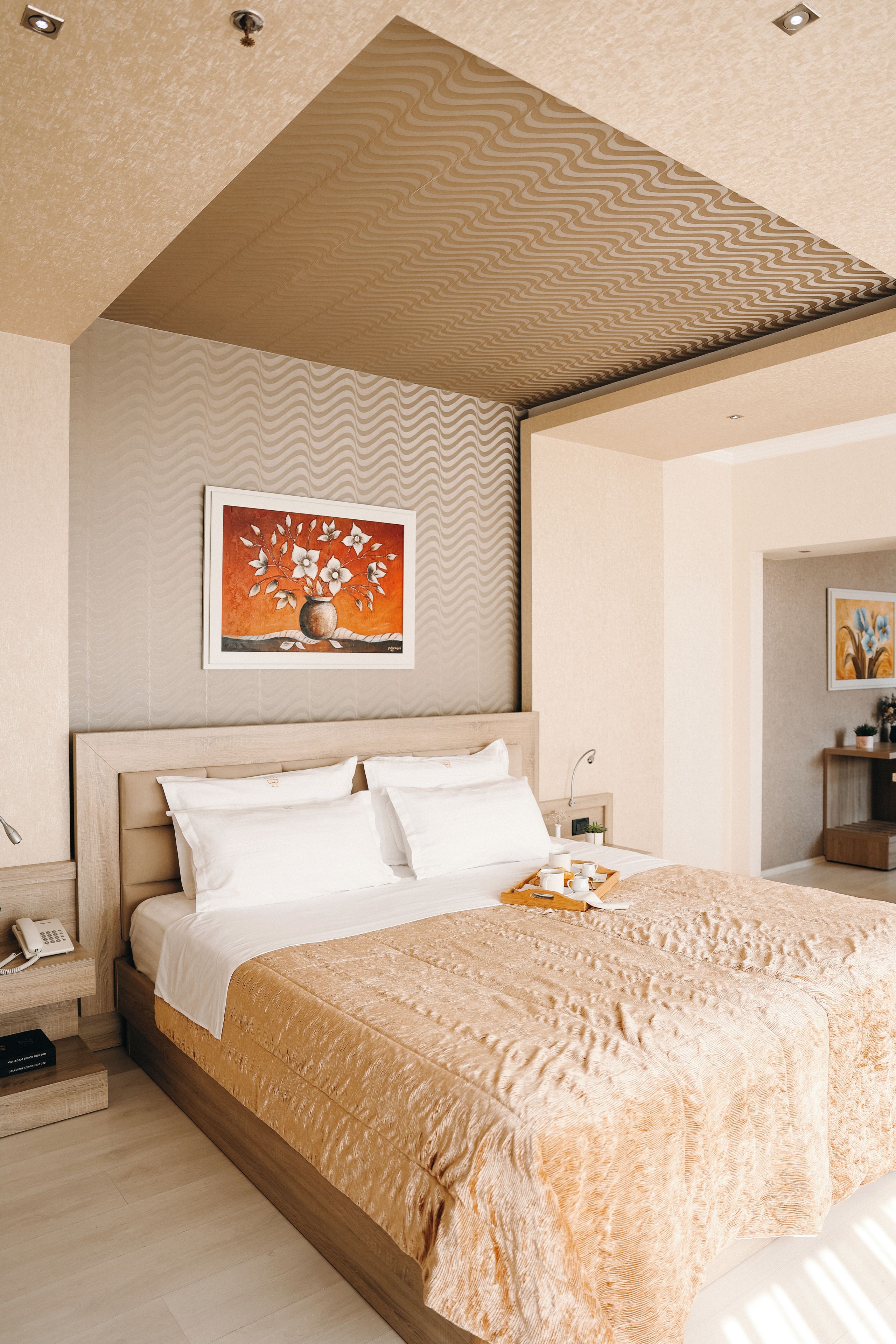 Ein Schlafzimmer mit einem großen Bett, einem hölzernen Kopfteil, einem Gemälde an der Wand und einem Nachttisch mit einer Lampe.