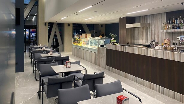A modern restaurant with a long counter, seating area, and a display case with food items. - Hotel Partner & Spa (Vlorë)