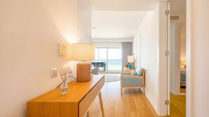 Ein modernes Hotelzimmer mit einem Holztisch, einer Lampe und Meerblick durch große Fenster.