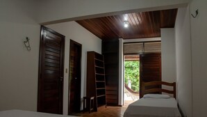 A bedroom with two beds, wooden doors, a bookshelf, and a hammock outside. - Casa Pipa Natureza Piscina Privativa 089 (Tibau do Sul)